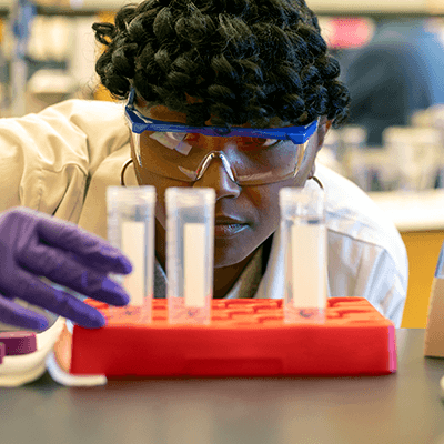 A student peering into test tubes in a lab.