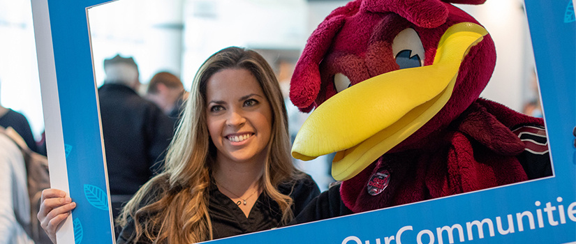 woman poses with Cocky at the E-Week Open House