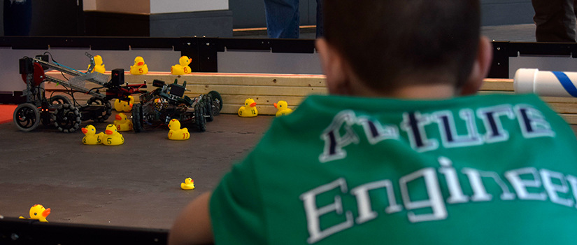 a young student looks at a robot