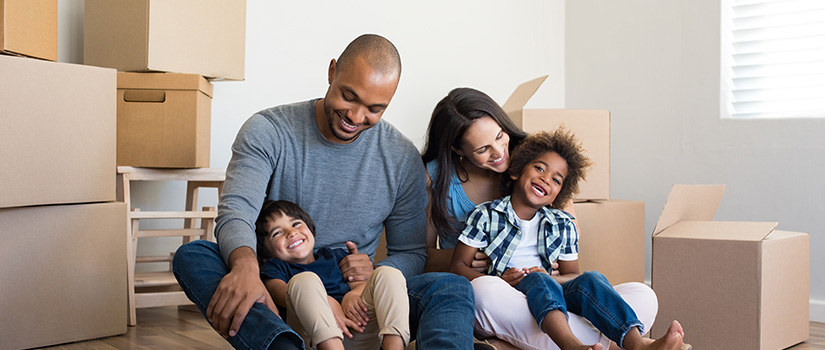 Family of four surrounded by moving boxes