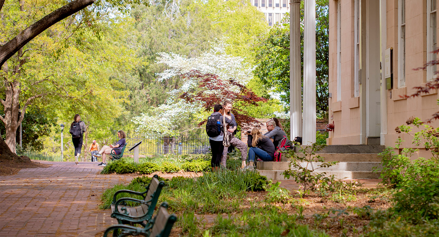 A group of students gathered at the steps of Rutledge Chapel with the brick path of the horseshoe beside them. 